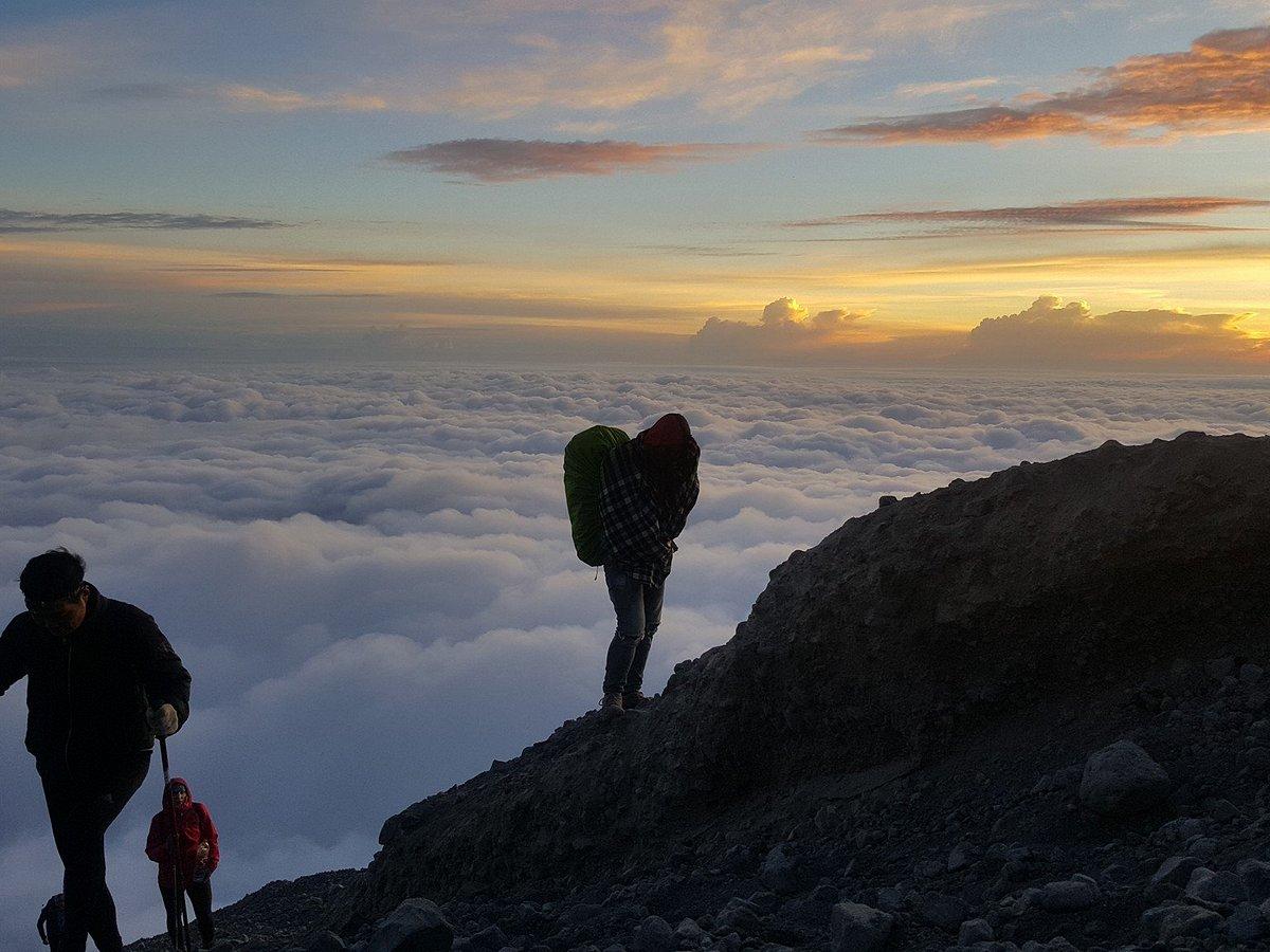 Trekkers on the Rinjani summit ridge above a sea of clouds at sunrise
